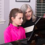 Female child learning to play the piano from teacher