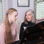 Piano teacher and female student at the piano